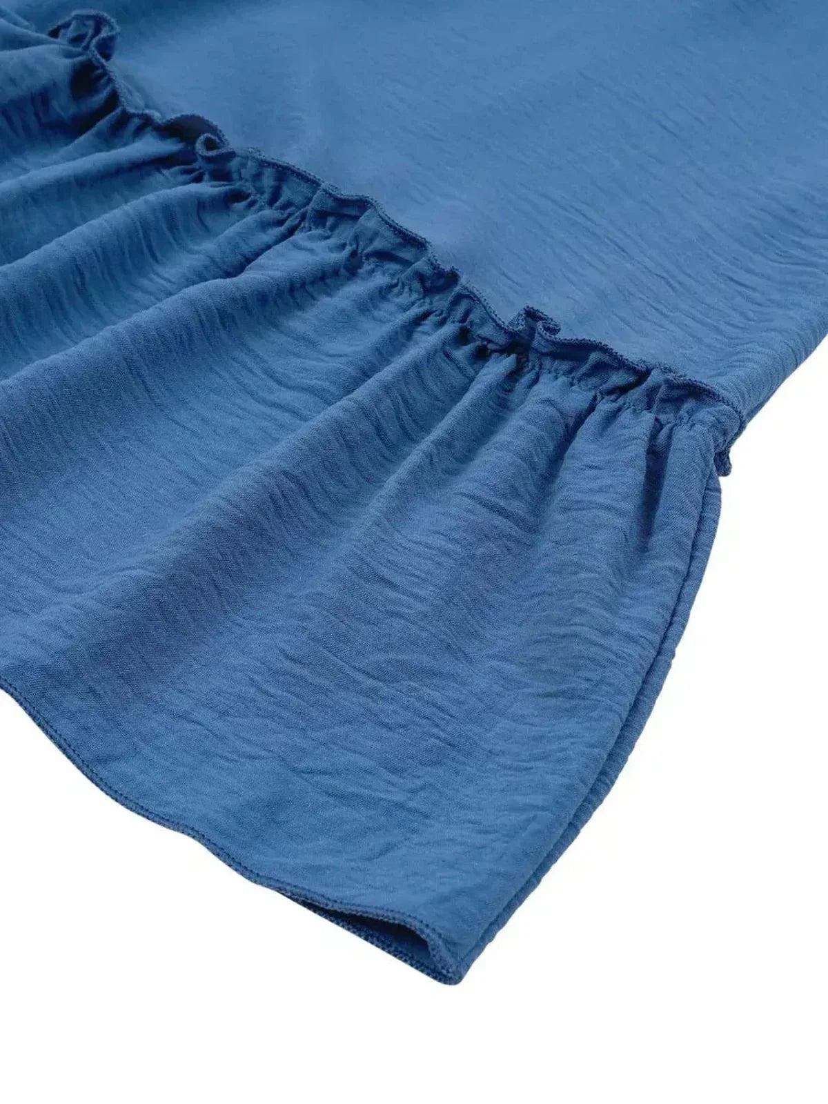 Close-up of the ruffled hem of the Blue Mirage Mini Dress in blue, showcasing lightweight fabric and feminine design.