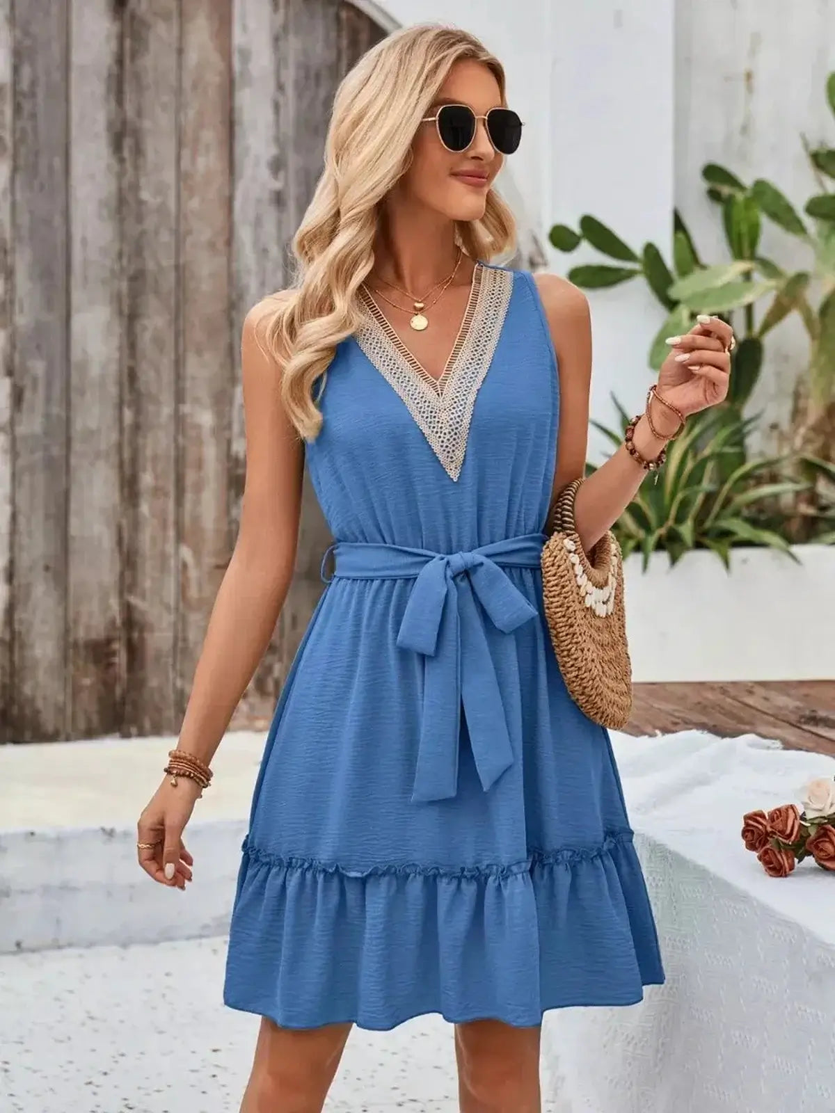 Model in a blue mini dress featuring a V-neckline, crochet lace trim, and a tie waist, perfect for summer occasions.