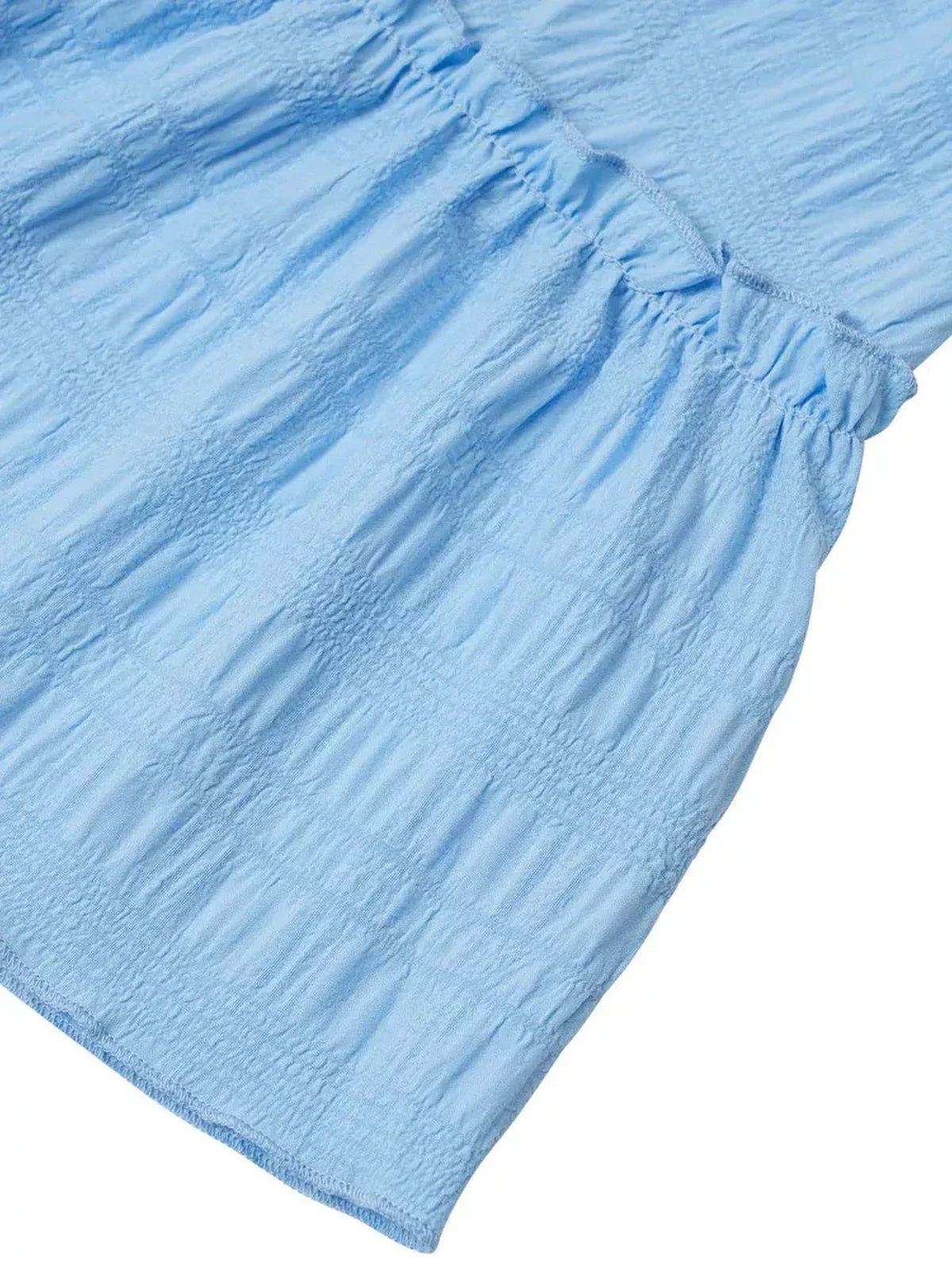Light blue fabric detail of a mini dress featuring textured ruching and a stylish silhouette.