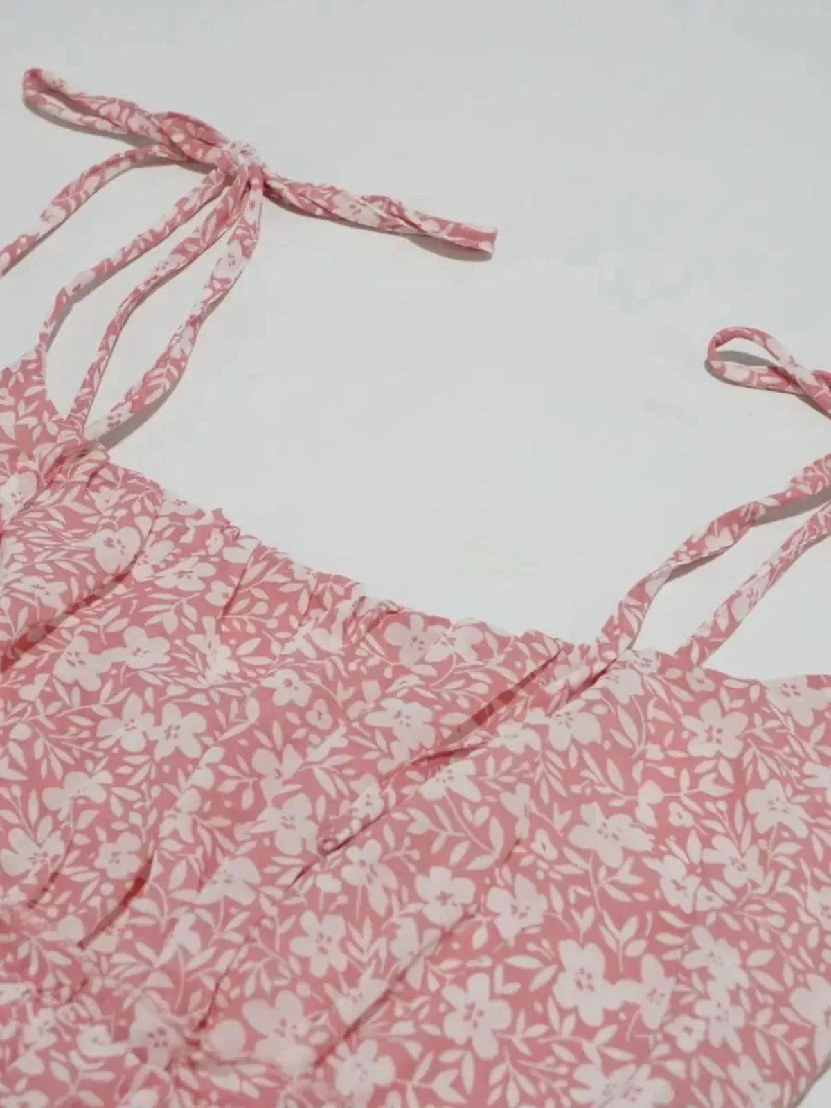 Close-up of the pink floral dress featuring delicate tie straps and a softly ruched bodice.