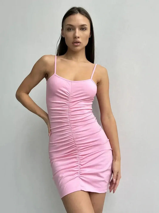 Model wearing a pink bodycon mini dress with adjustable spaghetti straps and stylish ruching.