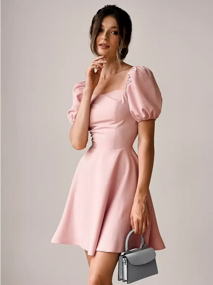 Light pink mini dress with puff sleeves and a square neckline, perfect for weddings and summer events.