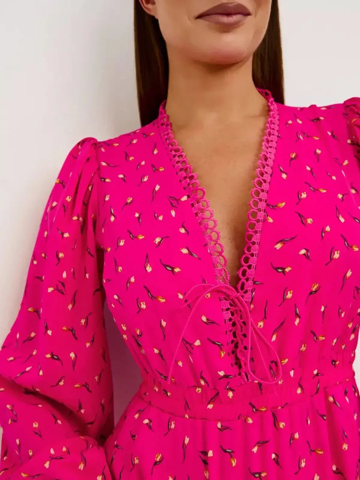 Model wearing a vibrant pink Tulip Bloom mini dress with lace trim and a deep V-neckline.