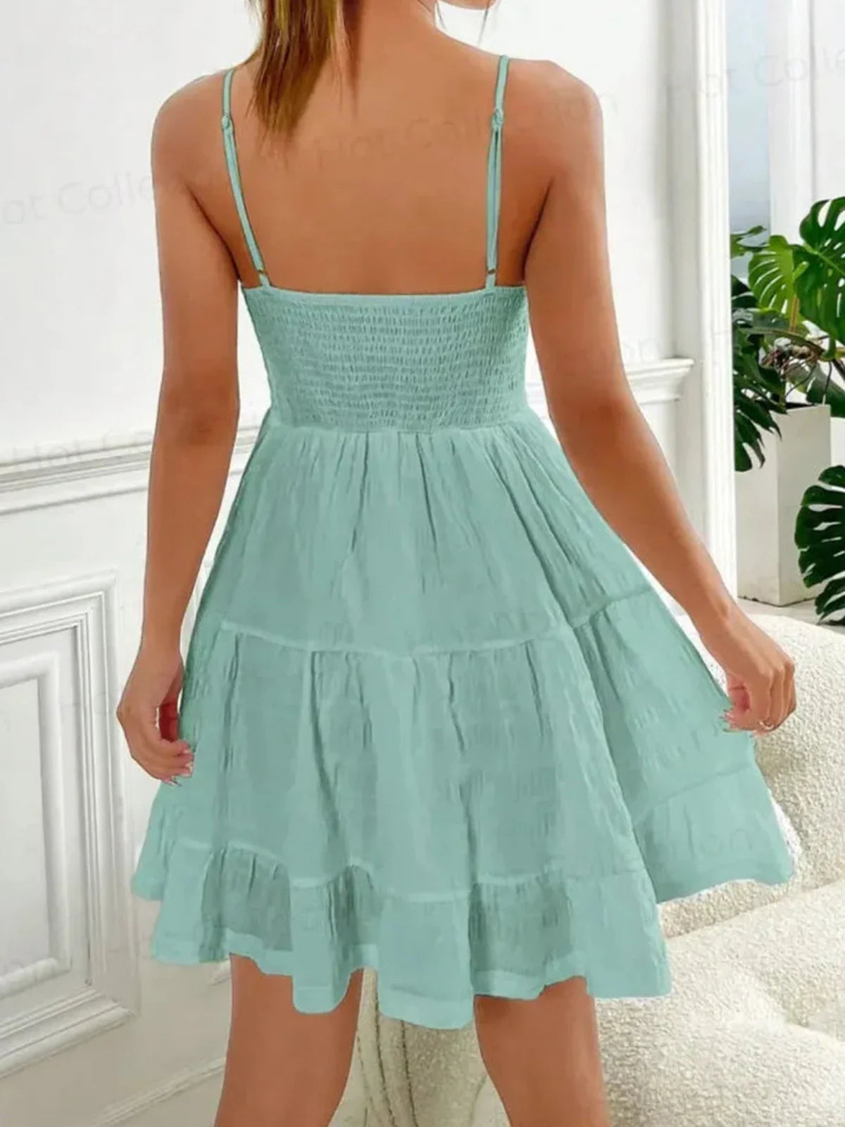 Back view of a soft mint tiered mini dress with a ruched bodice and flouncy hem, perfect for summer.