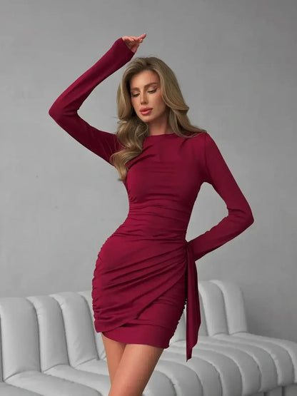 Burgundy Grace mini dress featuring long sleeves, ruched detailing, and a tied waist for an elegant and flattering fit.