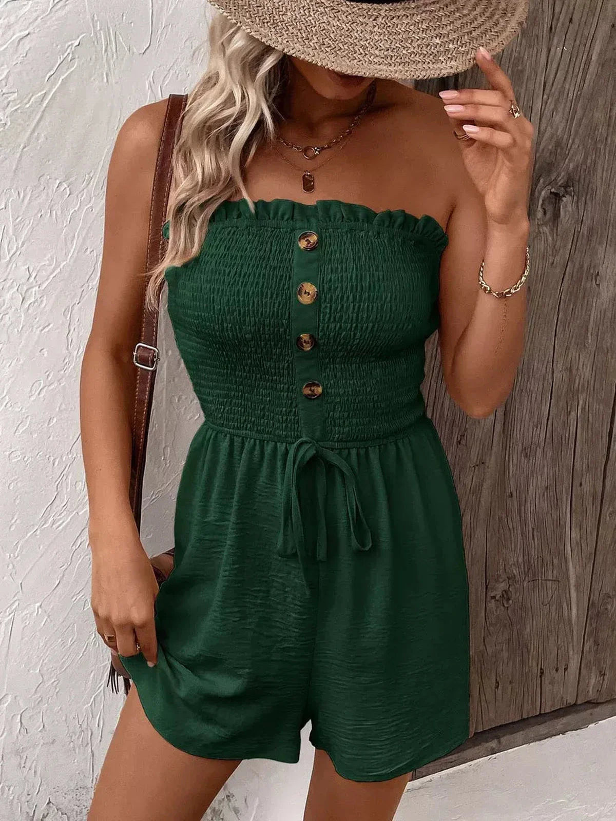 Woman wearing a green Buttoned Breeze Mini Dress with a smocked bodice and decorative buttons, perfect for summer.