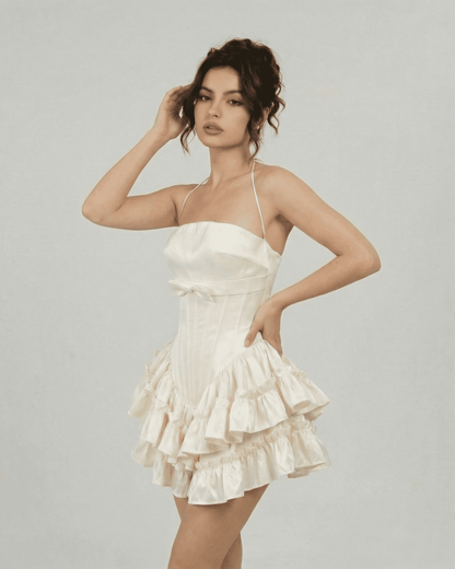 Celeste Mini Dress by Slimona, corset-inspired tiered design in soft white, featuring a sculpted bodice and halter straps.