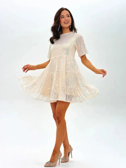 Model wearing a sparkling 'Champagne Pop' mini dress, perfect for summer celebrations and wedding guest attire.