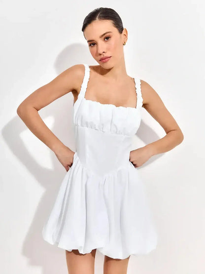 Model wearing a whimsical white mini dress with ruffled straps and a sculpted bodice, ideal for summer celebrations.