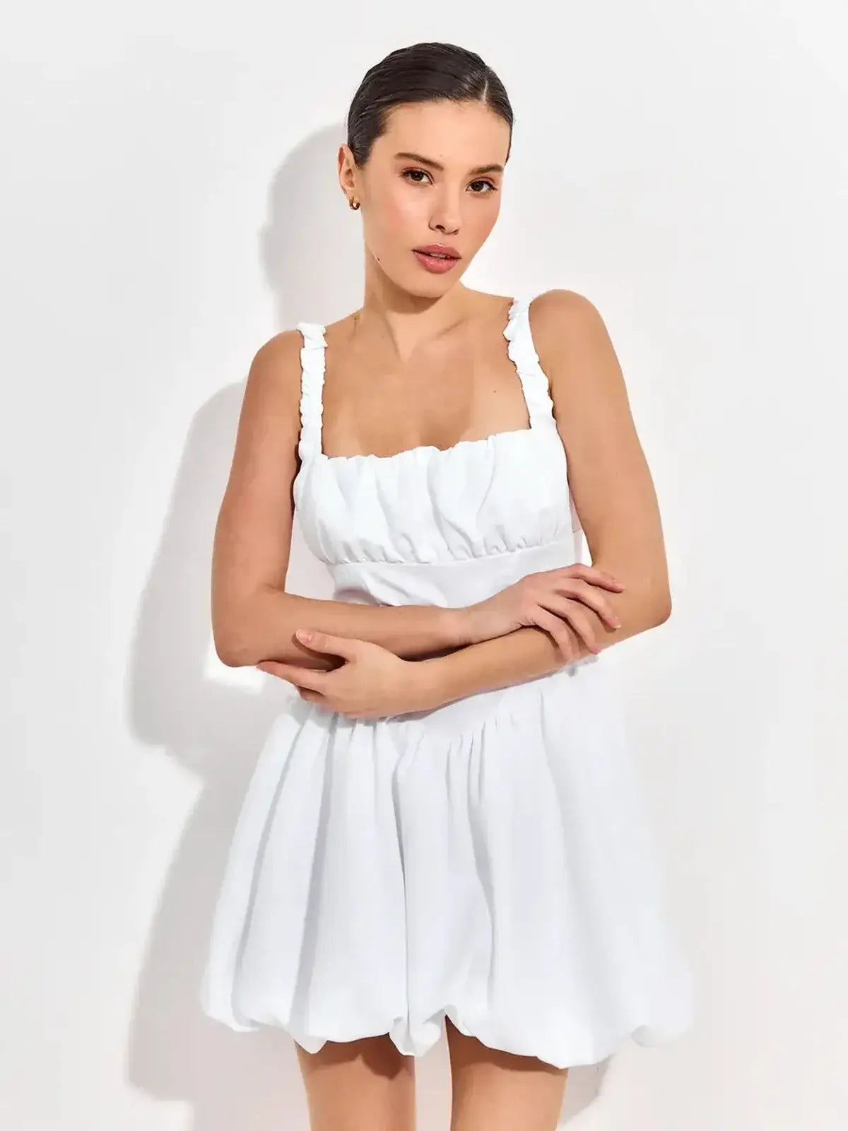 Whimsical white mini dress featuring a square neckline, soft ruching, and ruffled straps, perfect for summer celebrations.