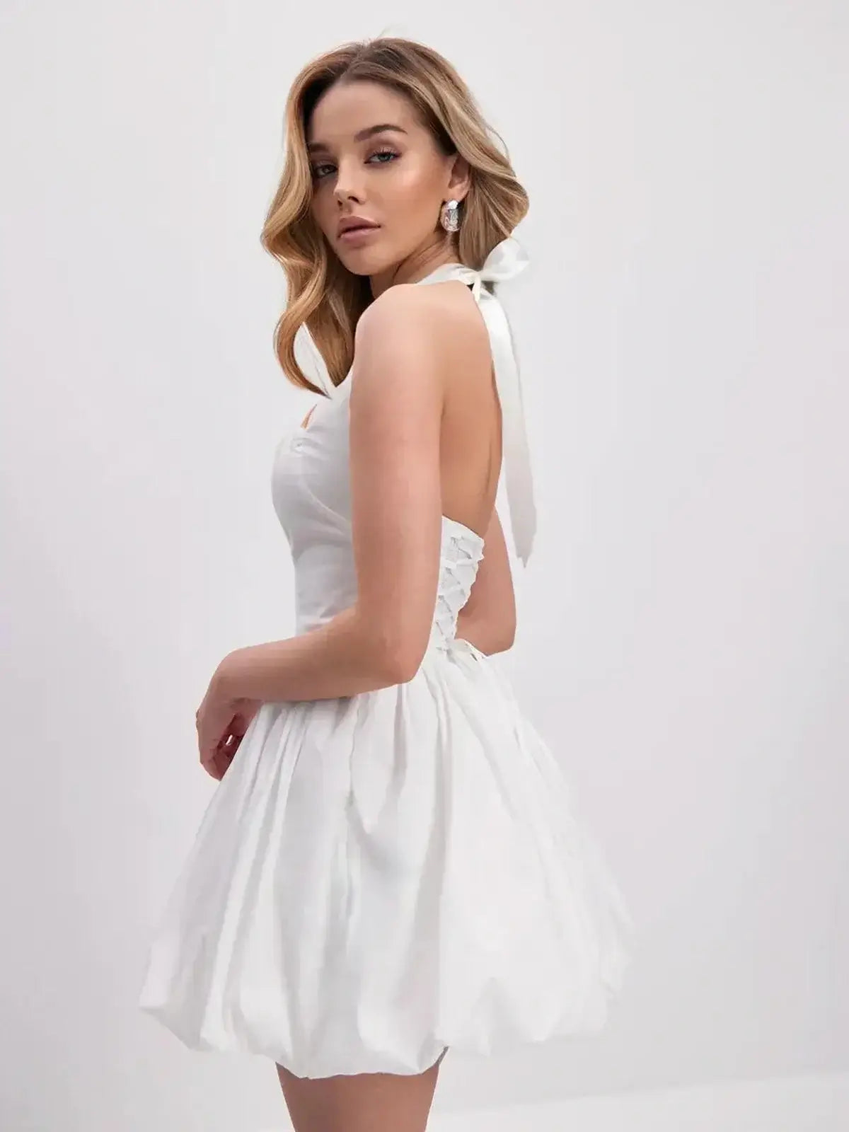 Model wearing the Cloud Belle white mini dress with halter neckline, voluminous bubble hem, perfect for summer or wedding events.