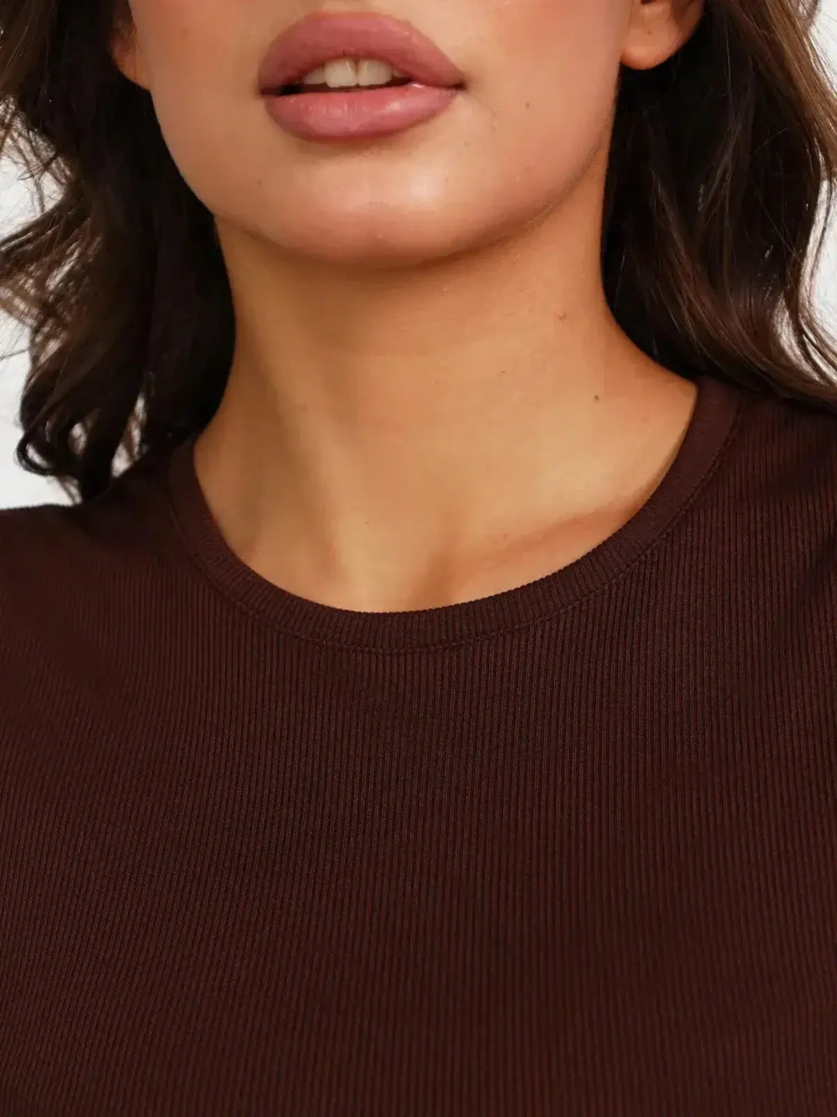 Close-up of a woman wearing a cocoa-colored ribbed knit dress, showcasing the U-neckline and soft fabric.