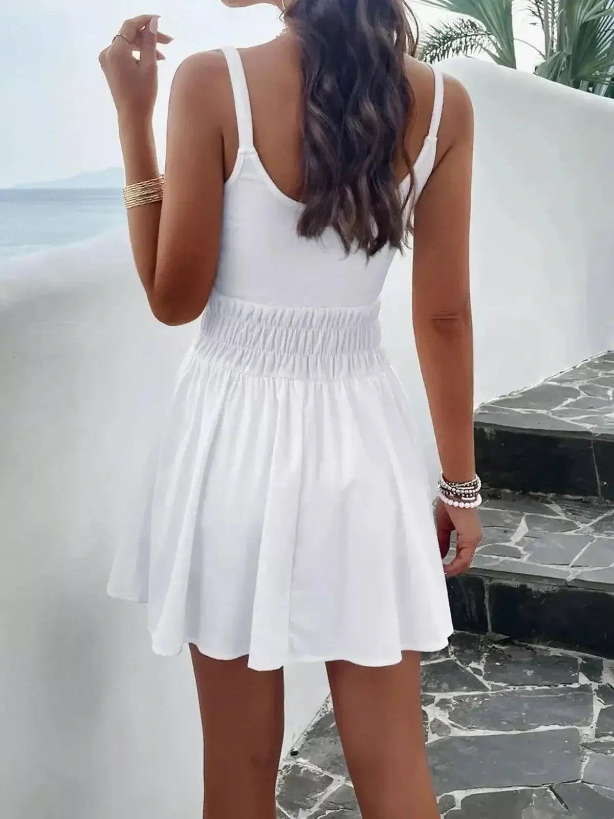Back view of a woman in a white mini dress, perfect for summer outings and beach vacations.