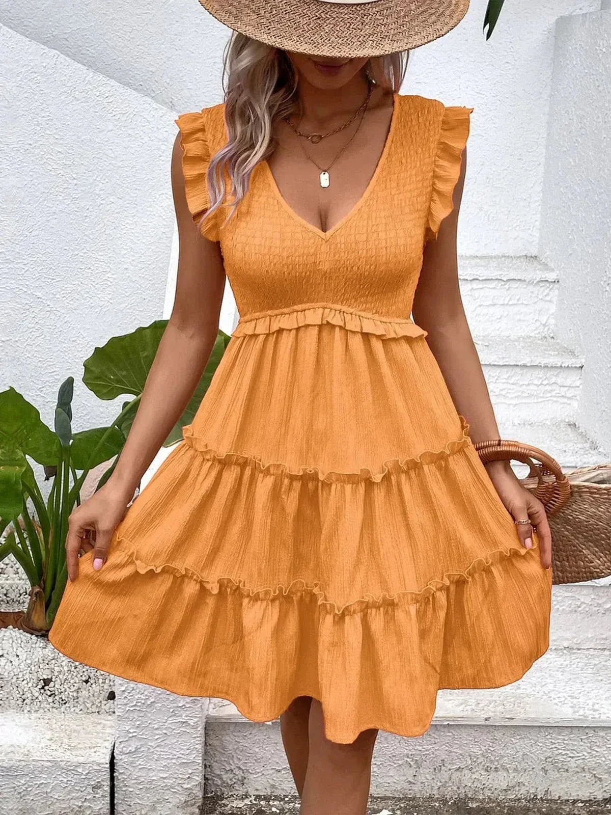 Woman wearing an orange Eden Tier Mini Dress with ruffle details, perfect for summer and casual occasions.