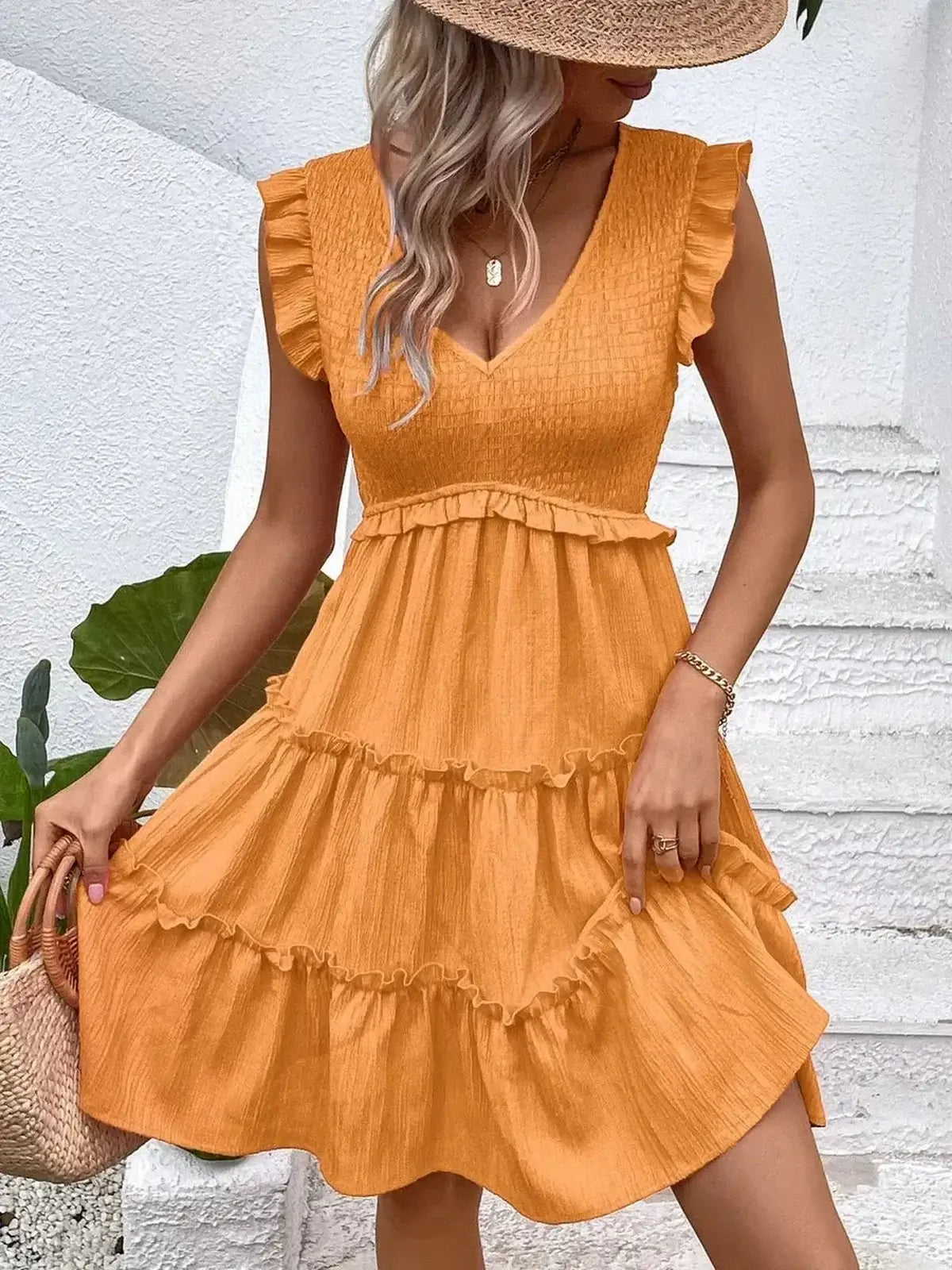 Eden Tier Mini Dress in vibrant orange with ruffles, V-neckline, and flutter sleeves, perfect for summer occasions.