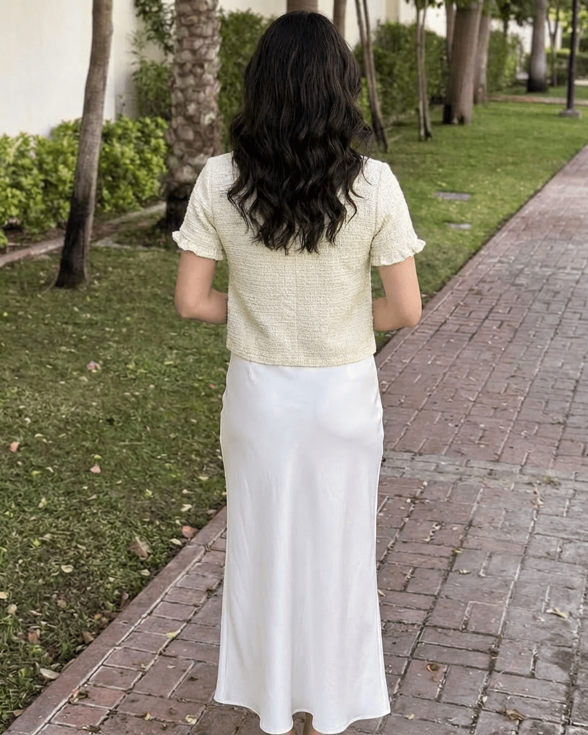 Elara Cardigan by Slimona, viewed from behind, showcasing the short sleeve design with white skirt in an outdoor setting.