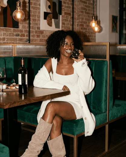 Elysia Mini Dress by Slimona, chic fitted knit dress styled with a cardigan, enjoying a drink in a stylish setting.
