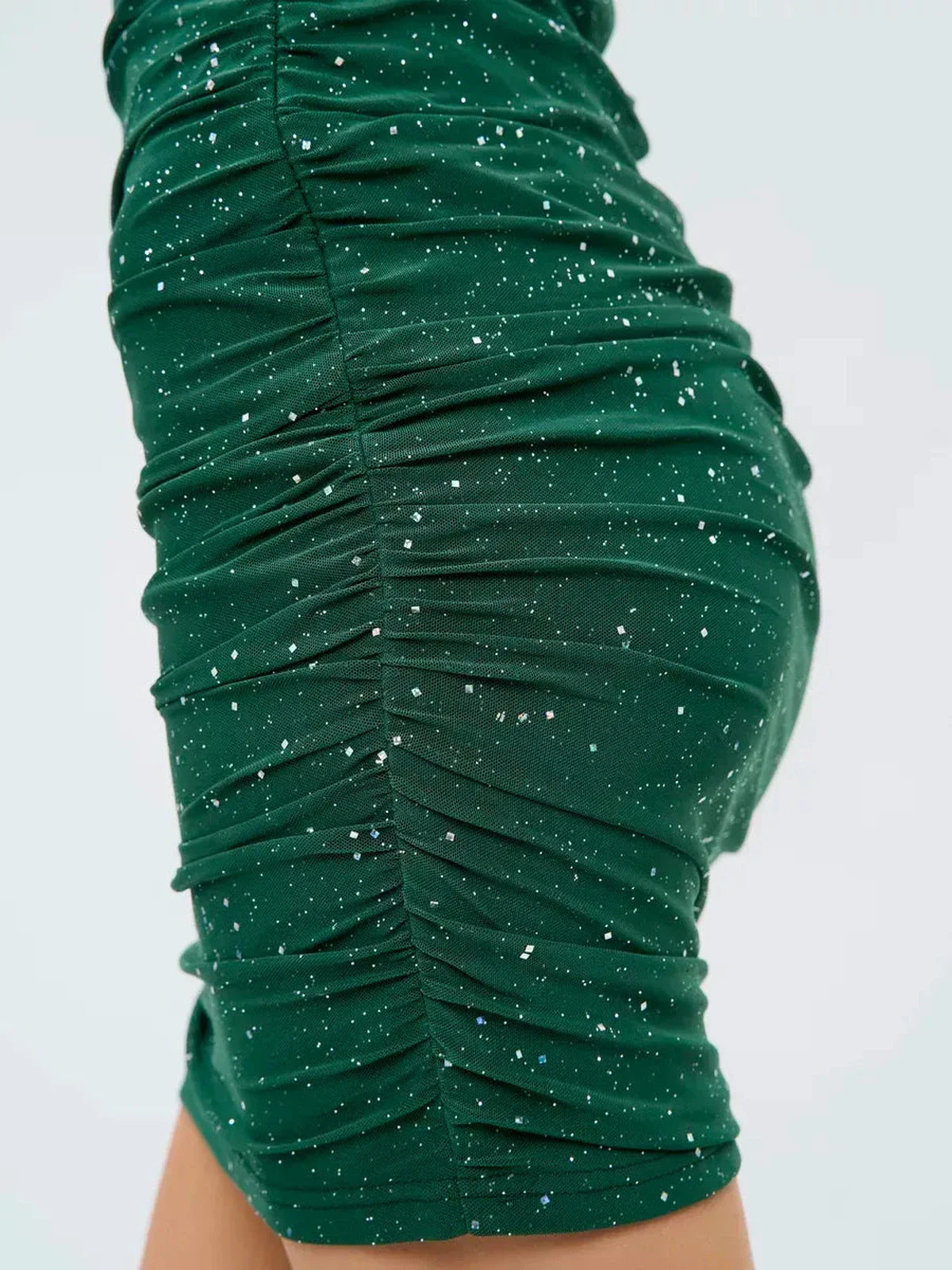 Emerald Spark mini dress showcasing ruched design and silver sparkle accents, perfect for parties and special occasions.