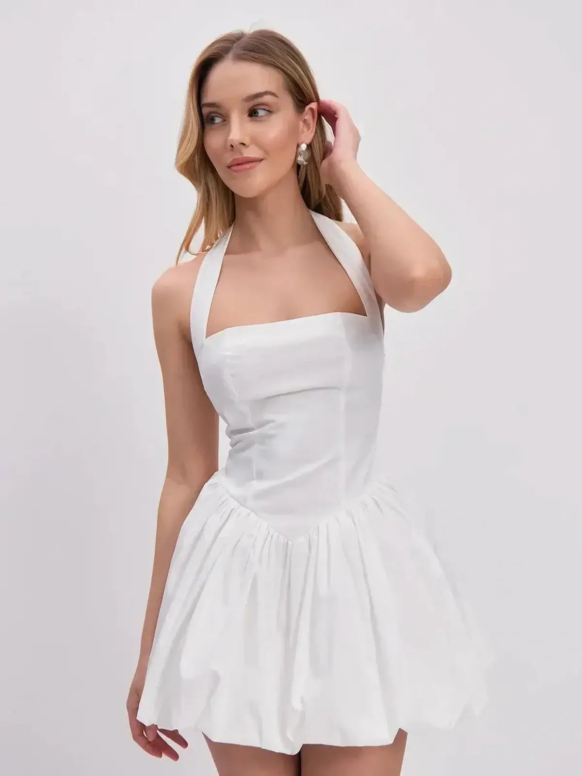 White mini dress featuring a halter neckline and gathered bubble hem, perfect for summer and special occasions.
