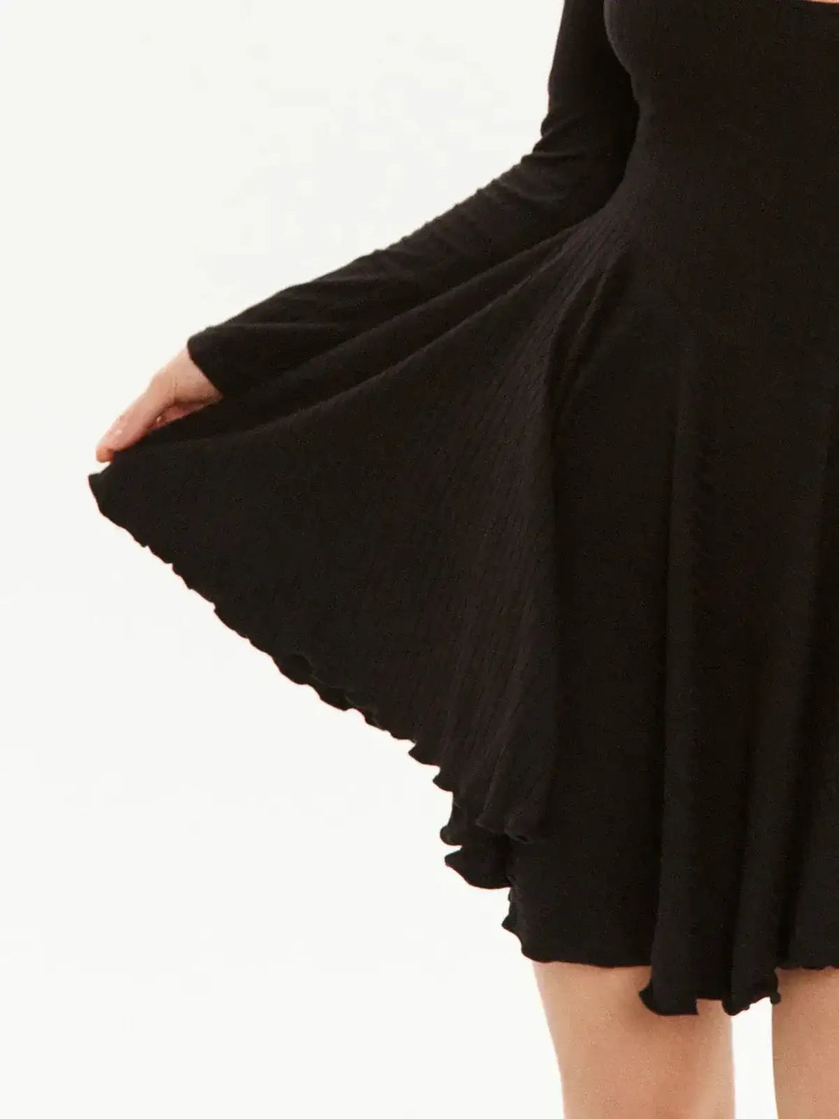Close-up of the Flare Muse black mini dress showcasing its flared hem and ruffled edges.