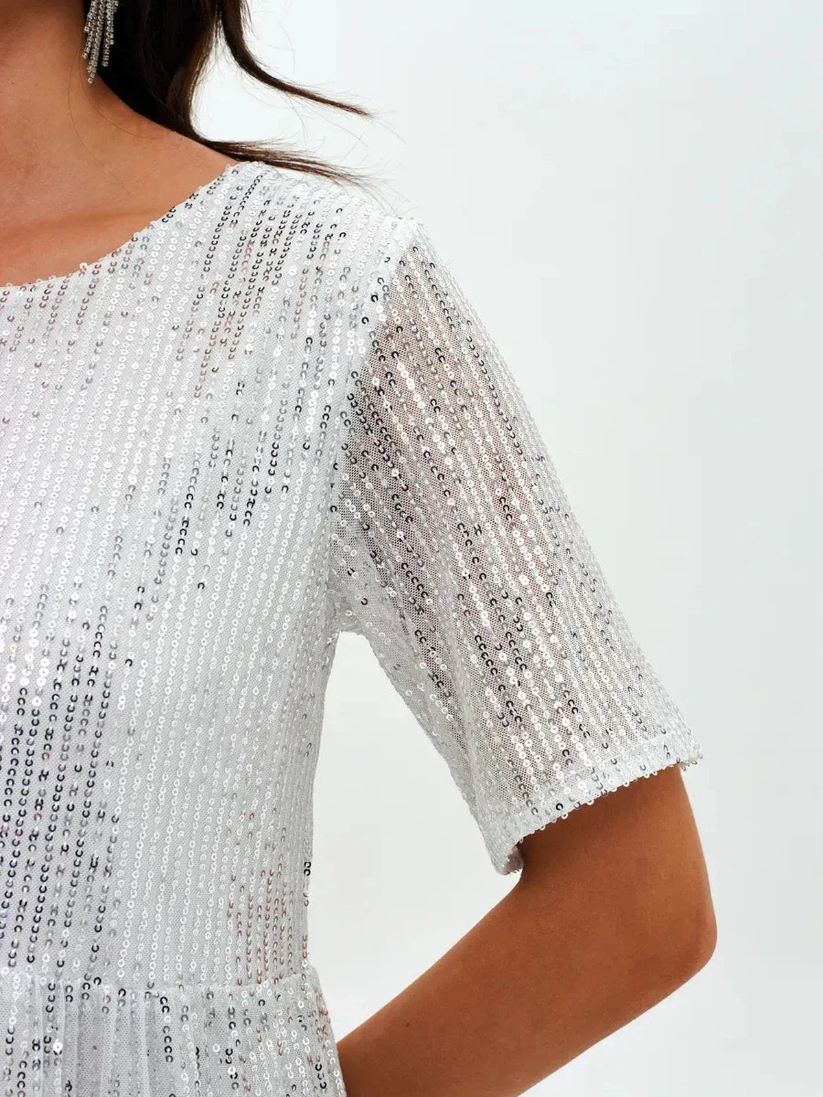 Close-up of the shimmering short sleeve of the sequin-adorned Frost Flicker white mini dress.