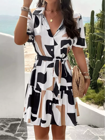 Woman wearing a GeoChic Mini Dress featuring a bold geometric pattern, short sleeves, and a tiered A-line cut.
