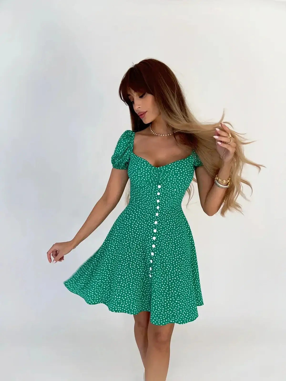 Woman wearing a green polka dot mini dress with puff sleeves and button detailing, perfect for summer or casual outings.