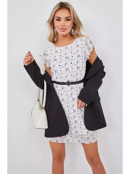 Model wearing the Heartline Charm white mini dress with black hearts, styled with a blazer and accessories.