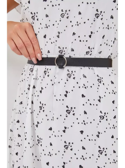 Close-up of black belt cinched at the waist of a white dress with scattered black hearts, showcasing stylish details.
