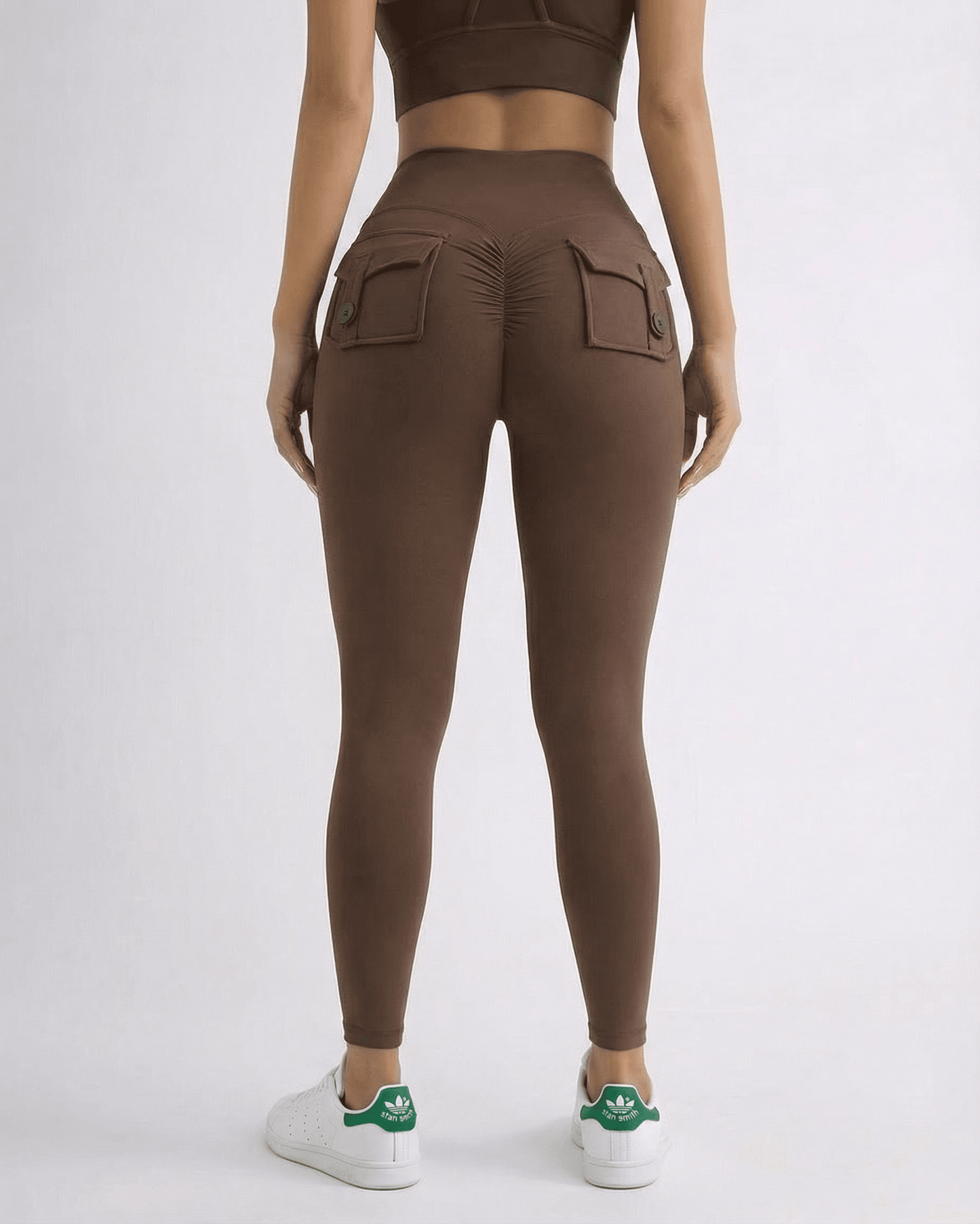 Woman wearing Hazel Leggings in brown, showcasing high-waist style and back pockets for added flair.