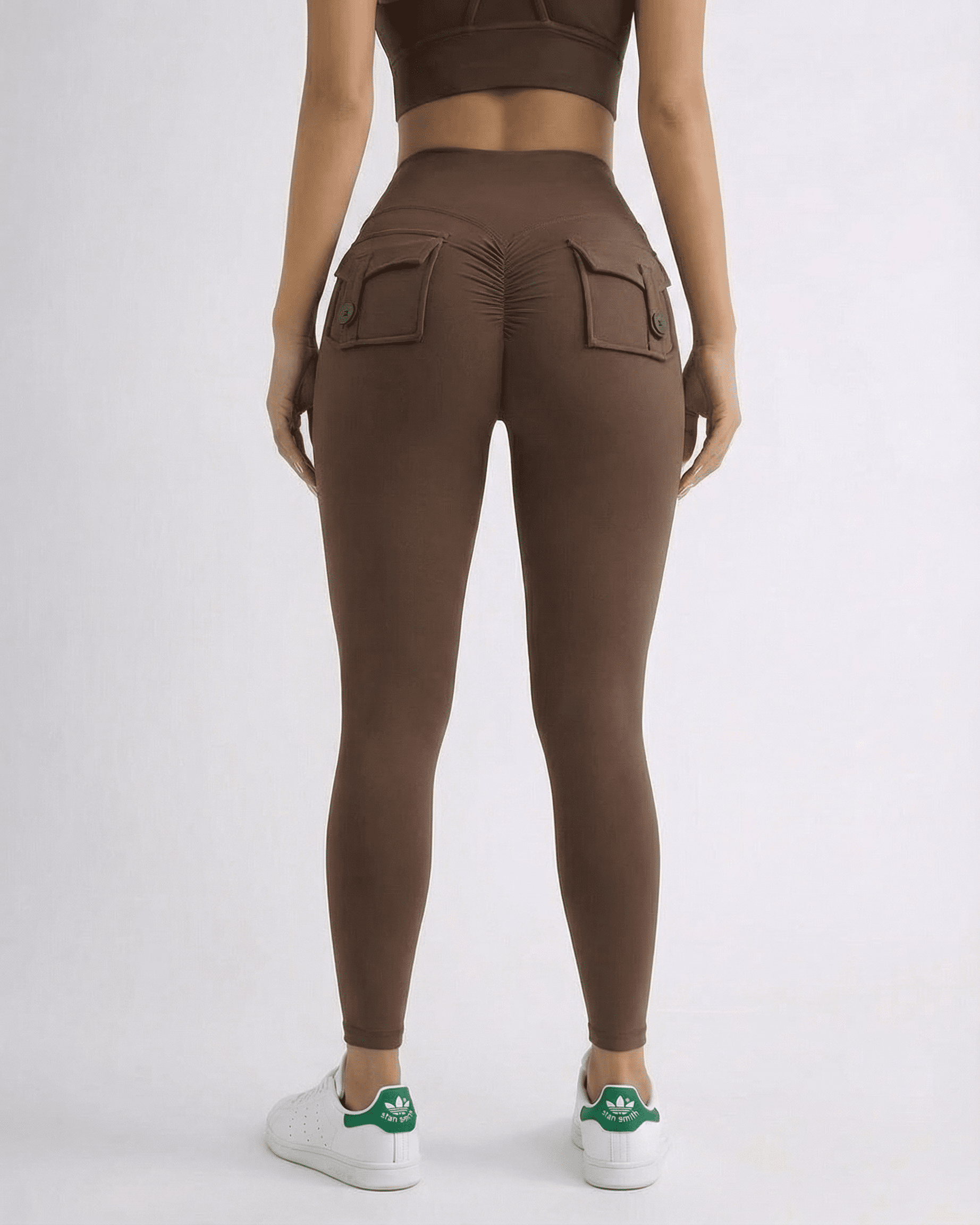 Woman wearing Hazel Leggings in brown, showcasing high-waist style and back pockets for added flair.