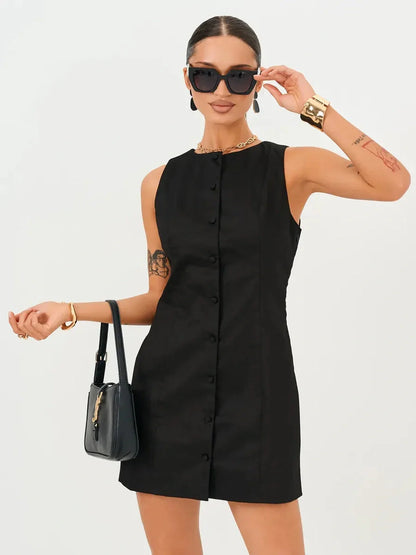 Stylish woman in a black mini dress with button detail, perfect for summer or evening occasions, accessorized with sunglasses.