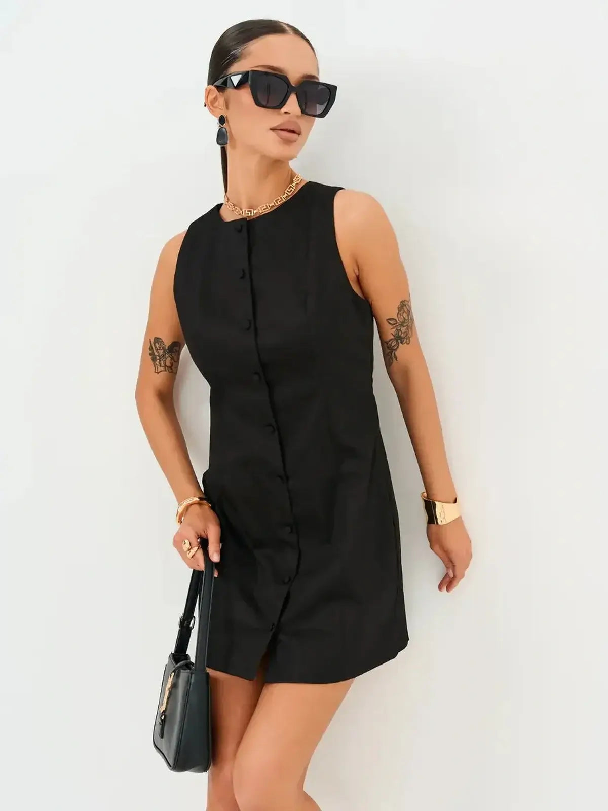 Sleek black Icon Edge Mini Dress with button detail, styled with accessories, perfect for summer occasions.