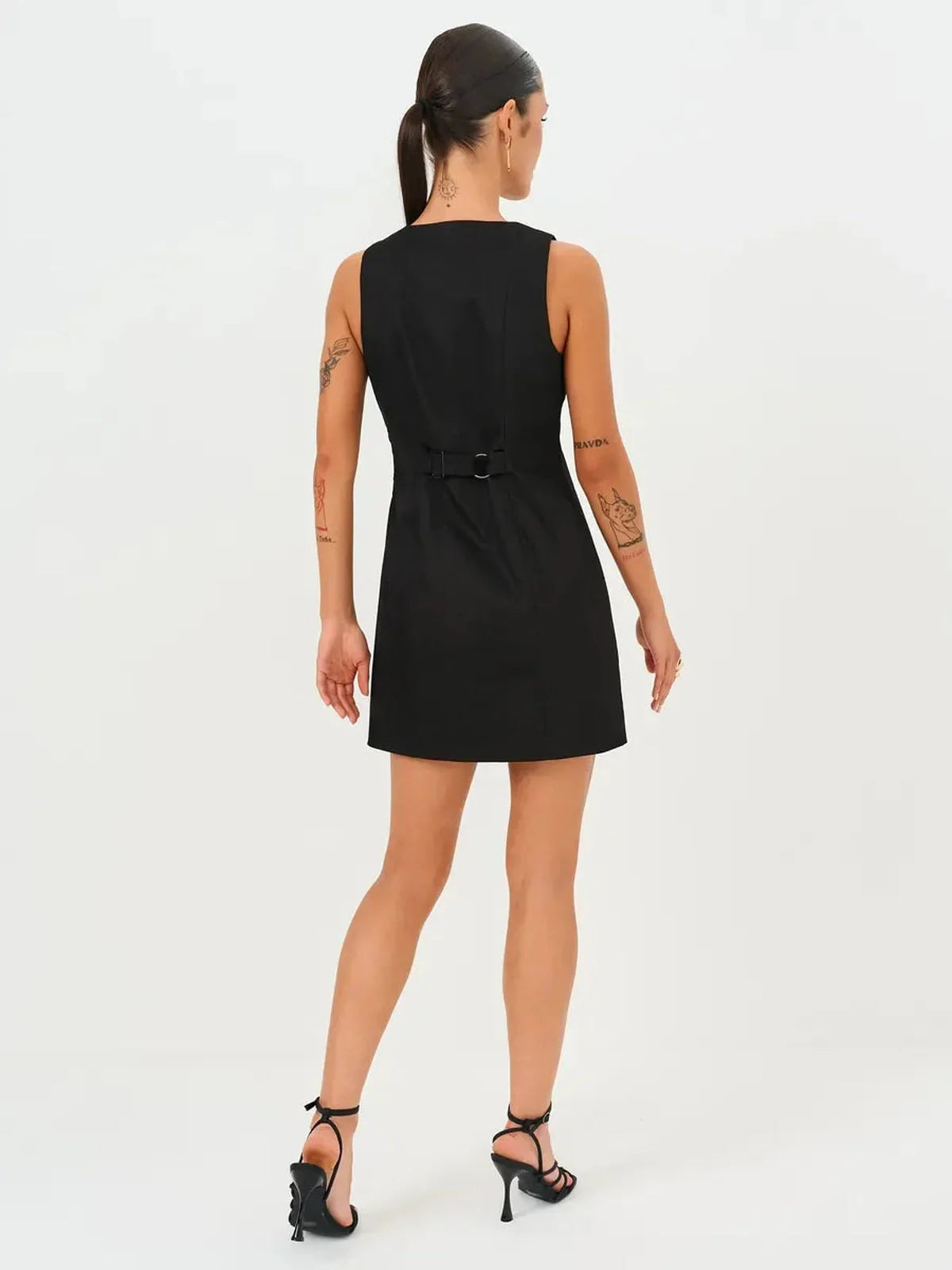 Back view of a black mini dress with a sleek silhouette and unique buckle detail, showcasing modern elegance.