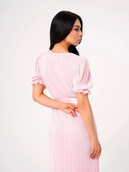 Back view of the pink pleated Celeste Maxi Dress featuring puff sleeves and a flattering tie waist.