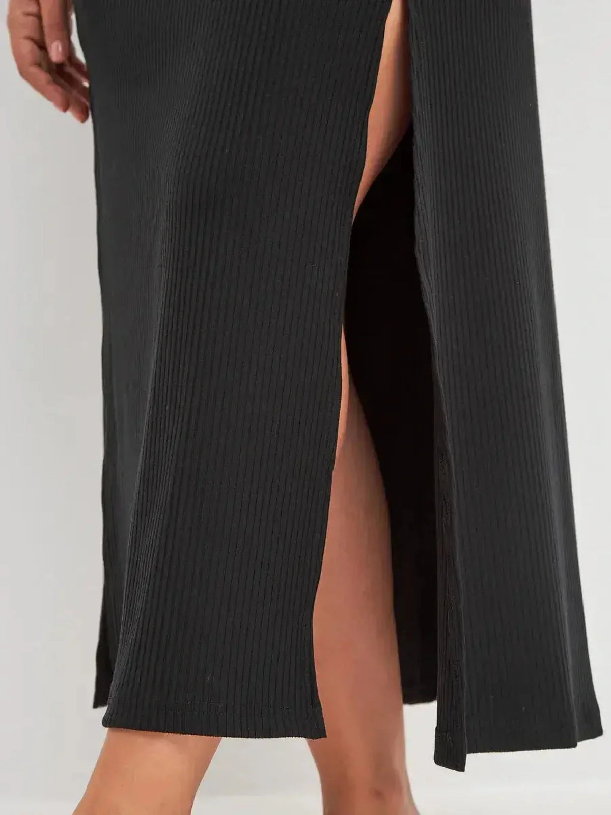 Close-up of black midi dress showing ribbed texture and high side slit for a stylish woman's outfit.