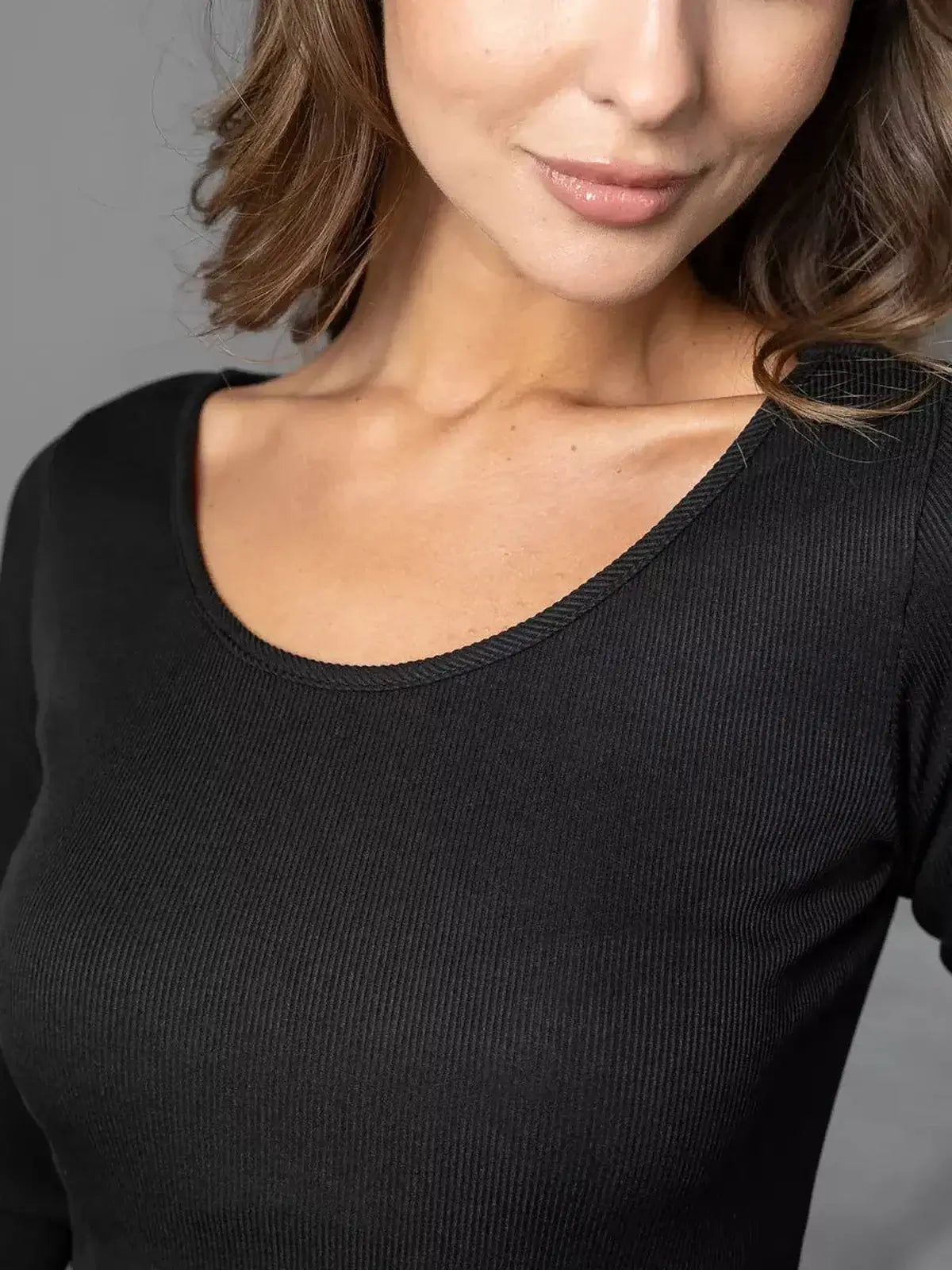 Close-up of a model showcasing the scoop neckline of the Noir Flare black mini dress, highlighting its ribbed texture.