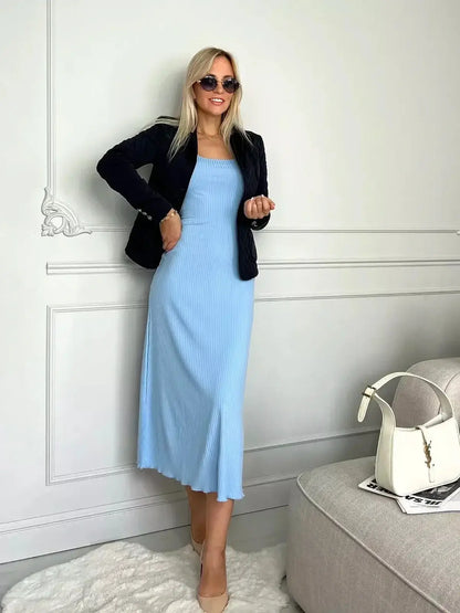 Model showcasing a Serene Lines Midi Dress in sky blue, styled with a blazer and sunglasses for a chic summer look.