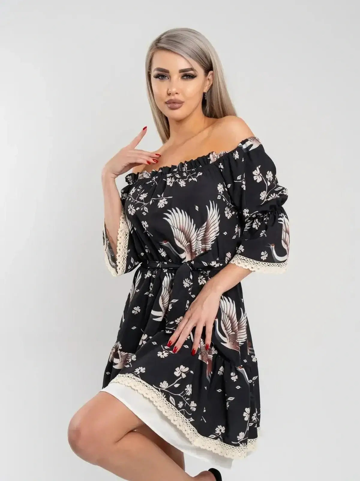 Model showcasing the Crane Bloom off-shoulder black mini dress with crane and floral print, perfect for summer and wedding guest occasions.