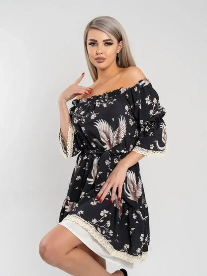 Model showcasing the Crane Bloom off-shoulder black mini dress with crane and floral print, perfect for summer and wedding guest occasions.