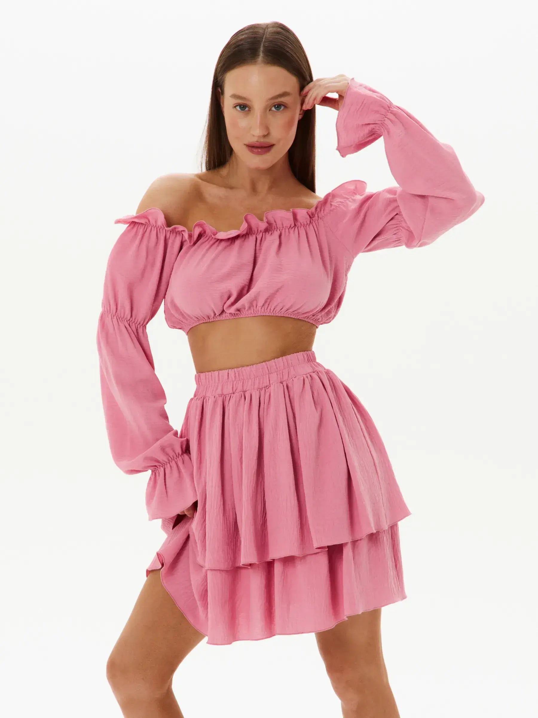 Feminine tiered ruffle set featuring an off-shoulder crop top and layered mini skirt in pink, perfect for summer and special occasions.
