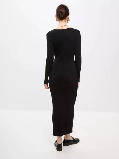 Back view of a woman wearing a black Sculpted Rib Maxi Dress, showcasing its long sleeves and body-skimming silhouette.