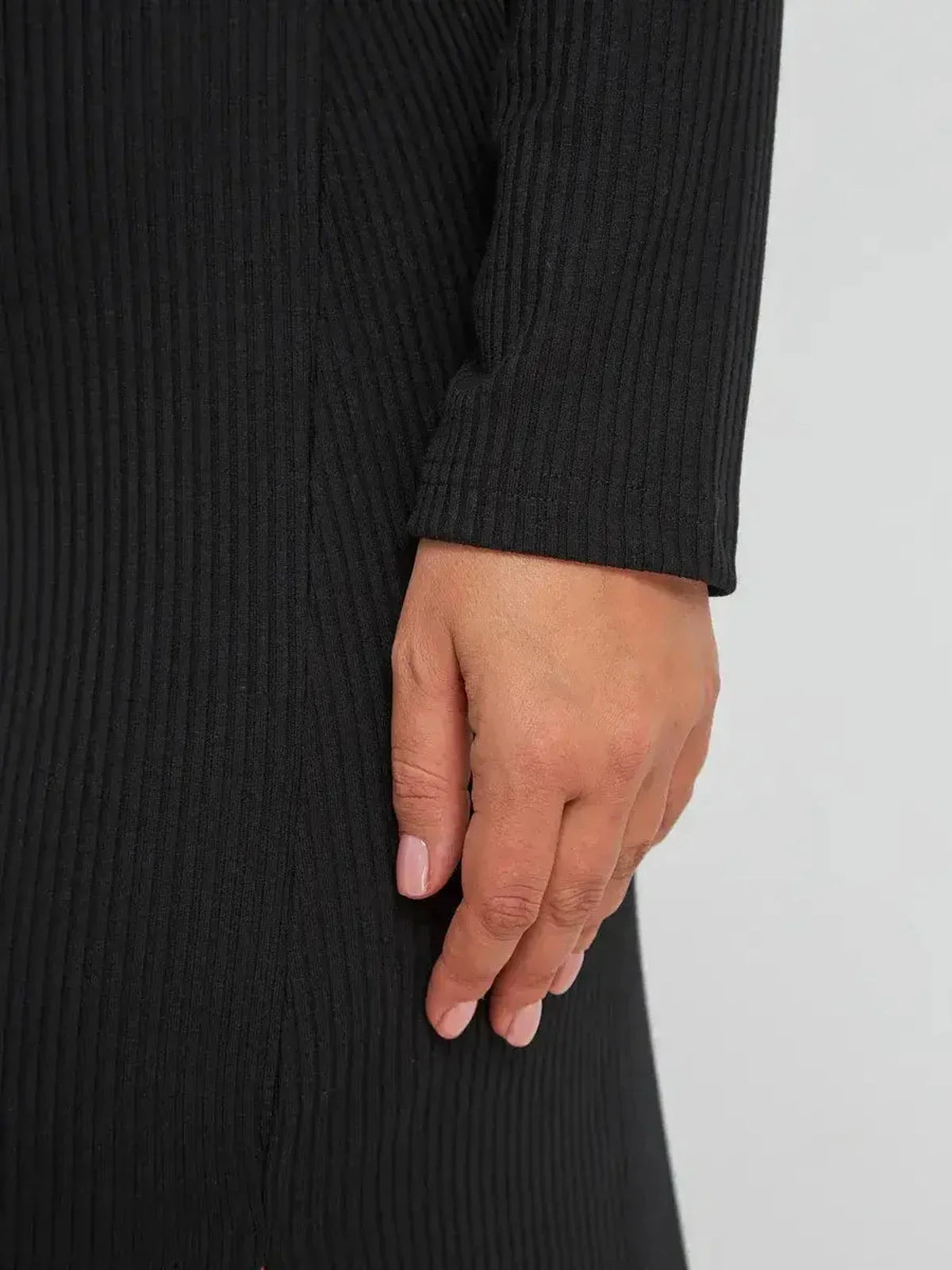 Close-up of a woman's hand on a ribbed black midi dress, showcasing its elegant texture and design.