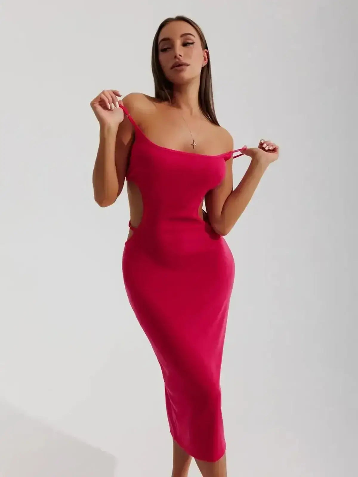 Model showcasing a Sculpt Midi Dress in vibrant pink, featuring side cutouts and a body-hugging silhouette, perfect for summer events.