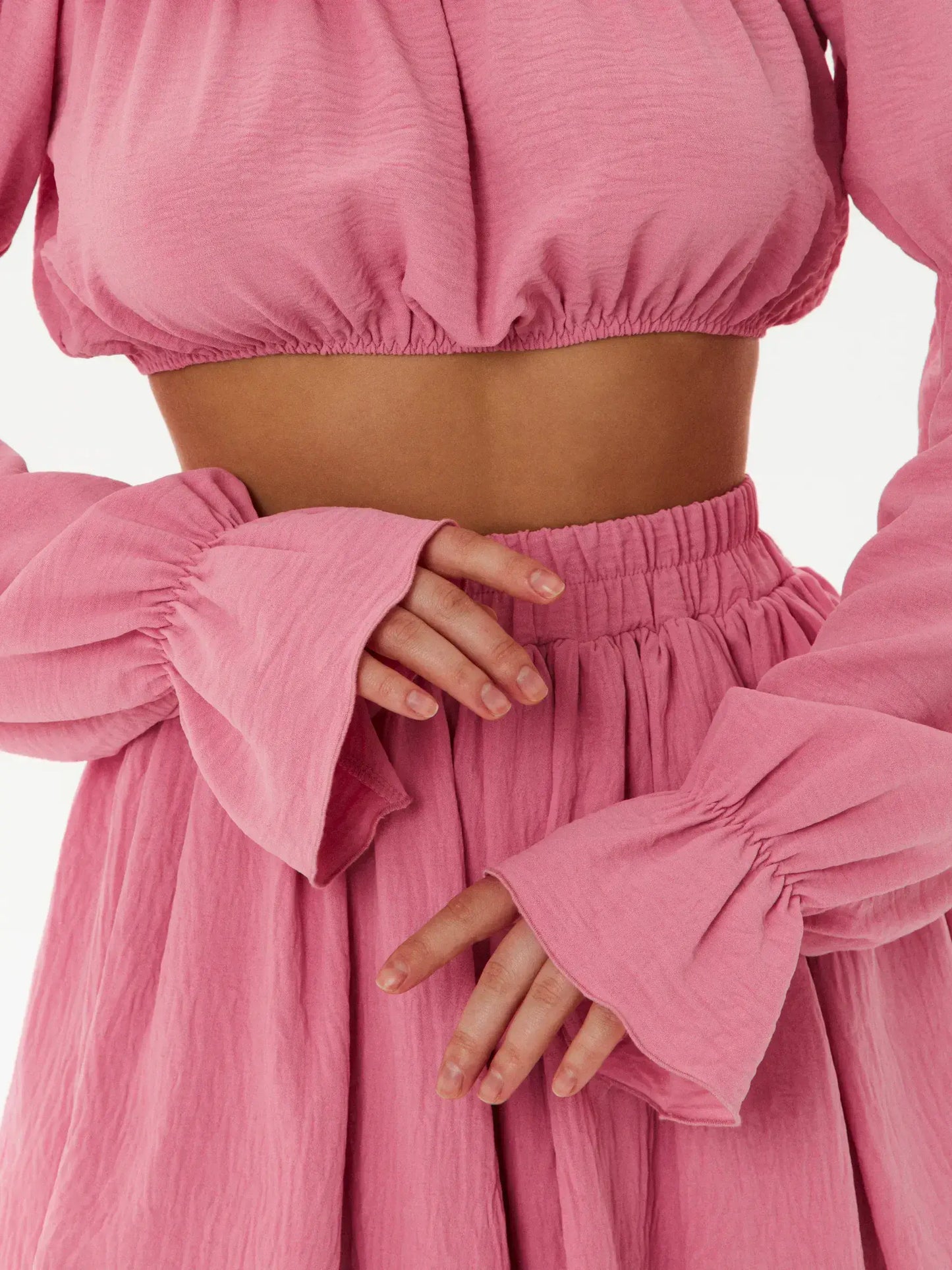 Close-up of a pink off-shoulder crop top and tiered mini skirt, showcasing ruffle details and feminine flair.