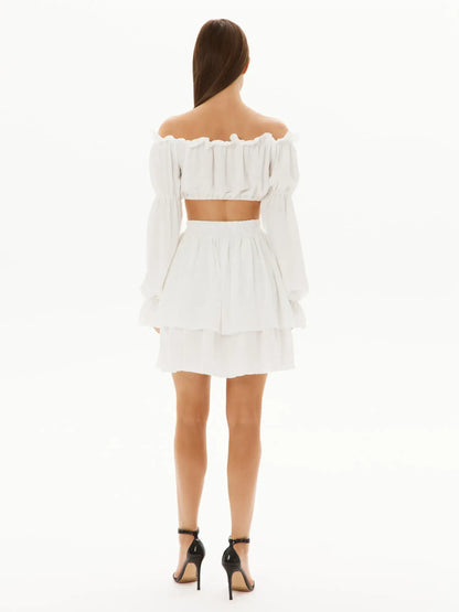Back view of a stylish white ruffle set featuring an off-shoulder top and layered mini skirt, perfect for summer occasions.