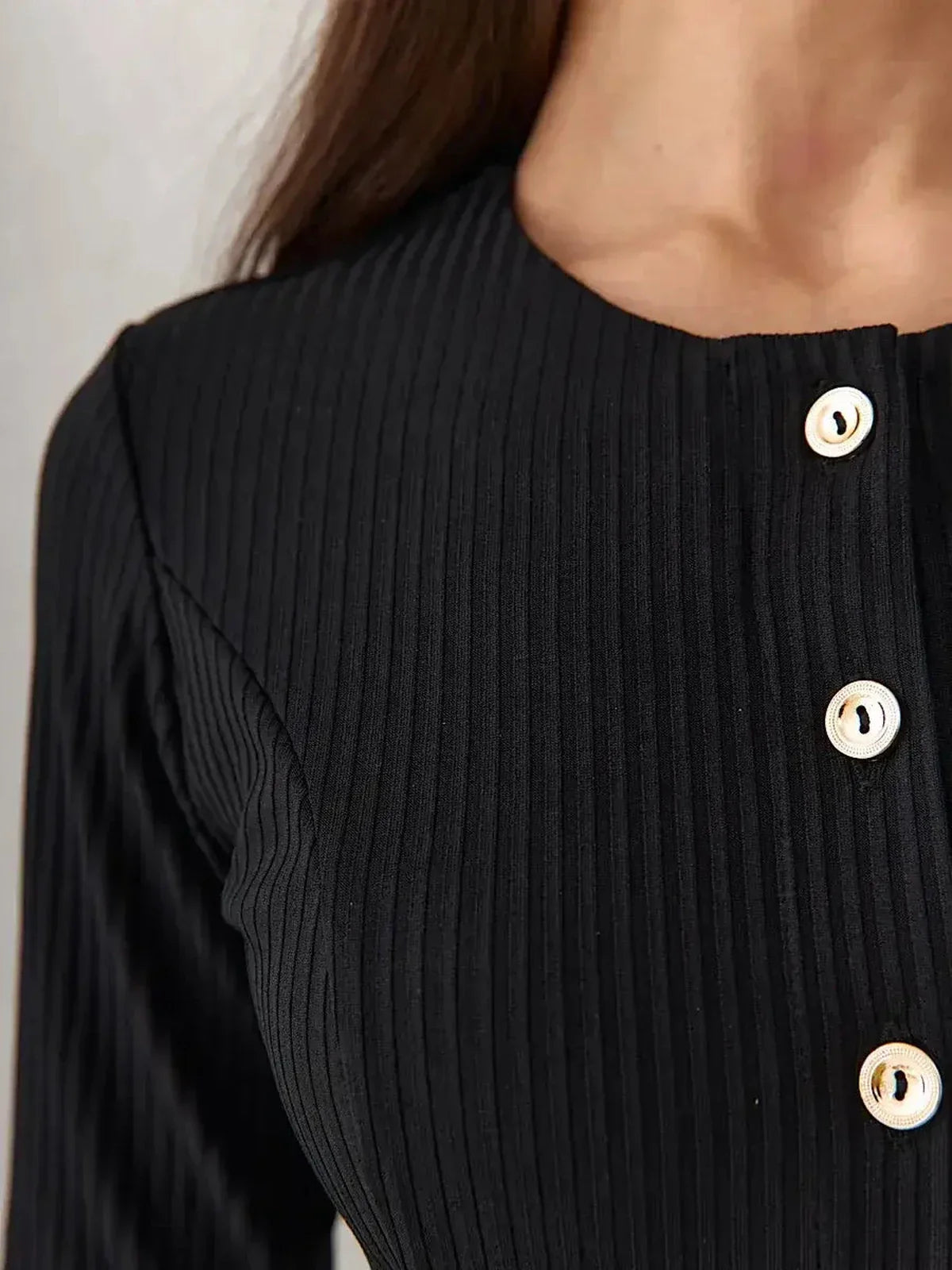 Close-up of the Serene Grace Midi Dress, featuring a ribbed black texture and decorative buttons for a chic look.