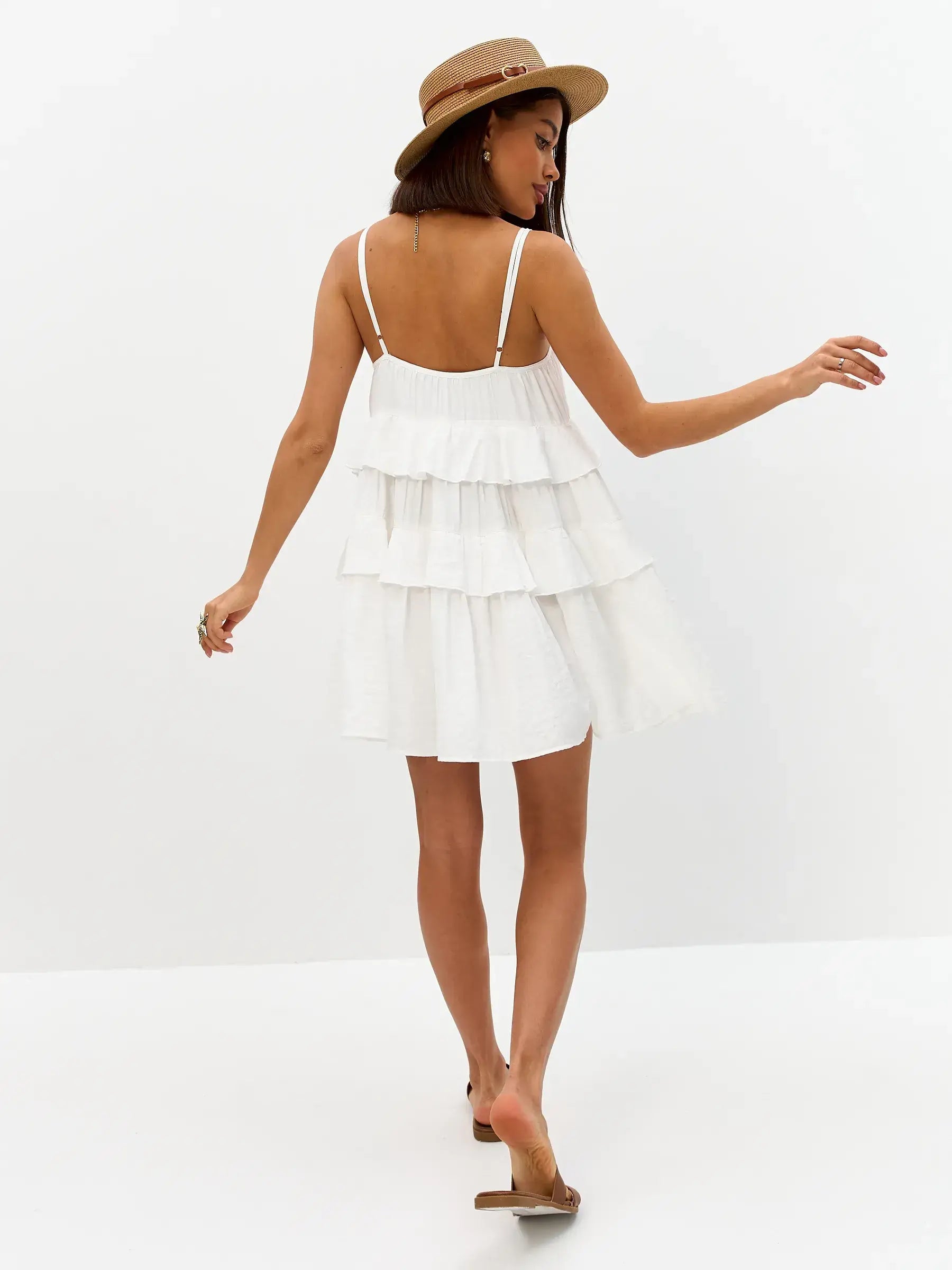 Model wearing the Riviera Ruffle white summer dress with tiered ruffles, showcasing a flared silhouette and delicate straps.