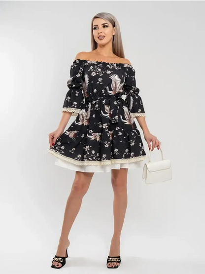 Model wearing a stylish off-shoulder black Crane Bloom mini dress with floral print, perfect for summer weddings and special occasions.