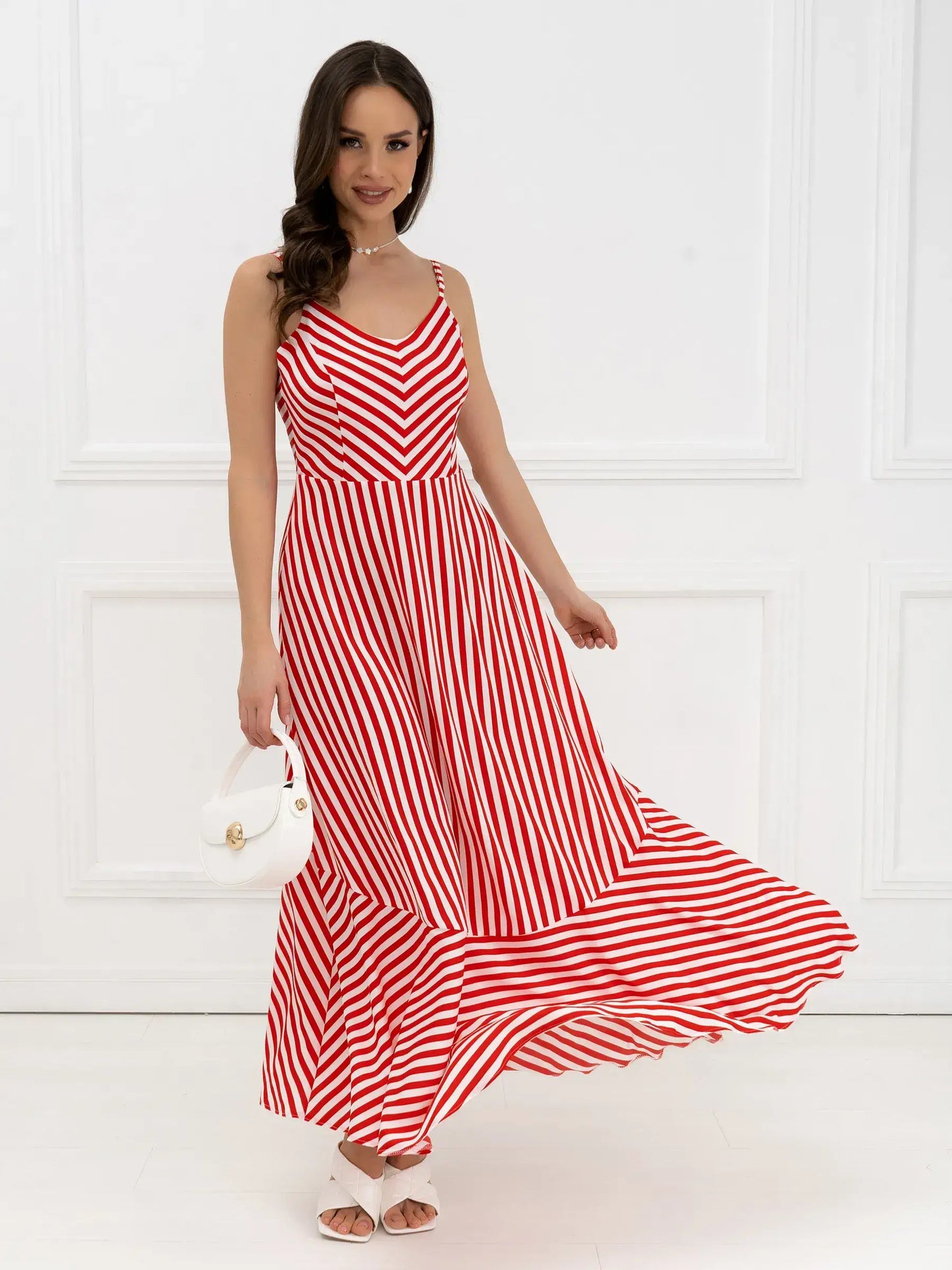 Model in a red-and-white striped maxi dress with a tiered hem, perfect for summer and wedding guest occasions.